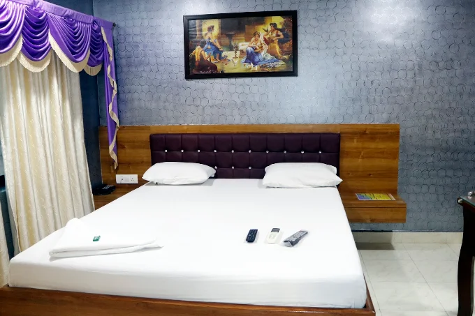 Guest room with white bedding, wooden headboard and purple upholstered headboard